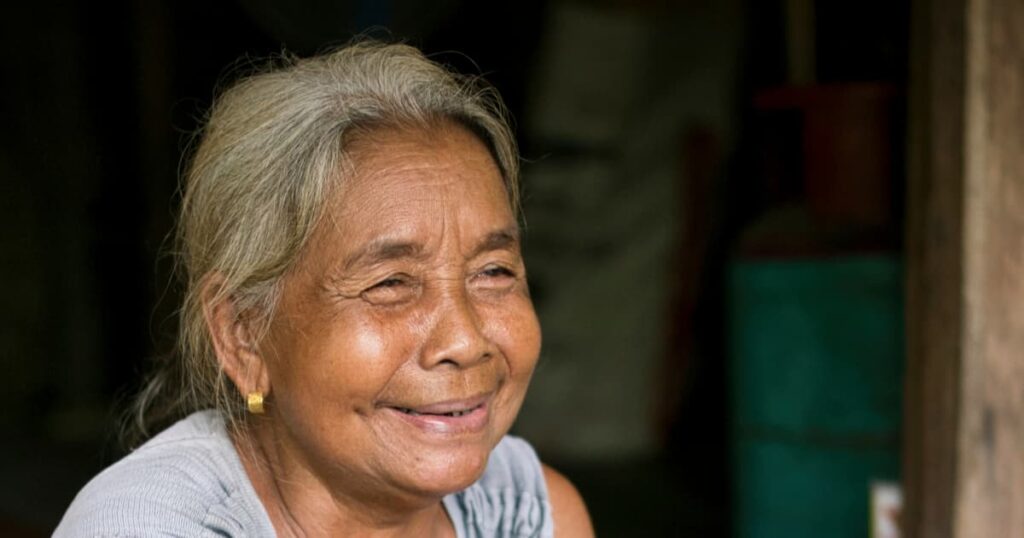 Smiling elderly woman in a coastal community, representing the human aspect of seaweed farming.