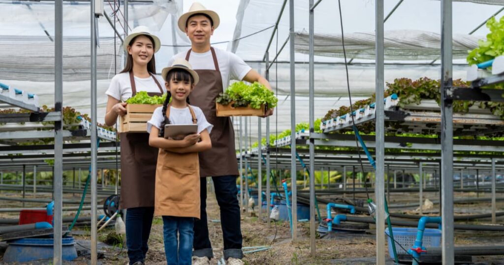 A family of three proudly showcasing their harvest in a sustainable farm.