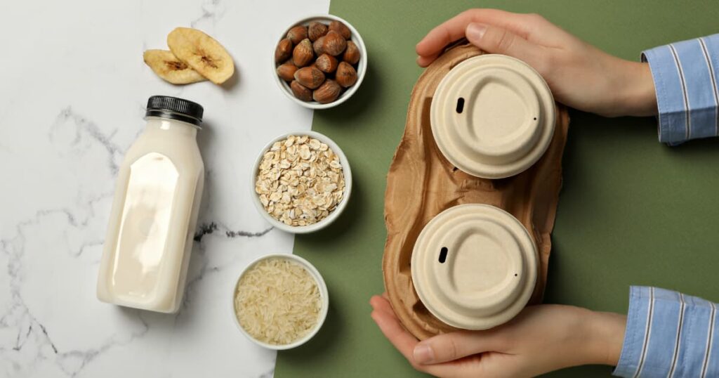 Hands holding eco-friendly coffee cups with various natural ingredients like oats, rice, and nuts.